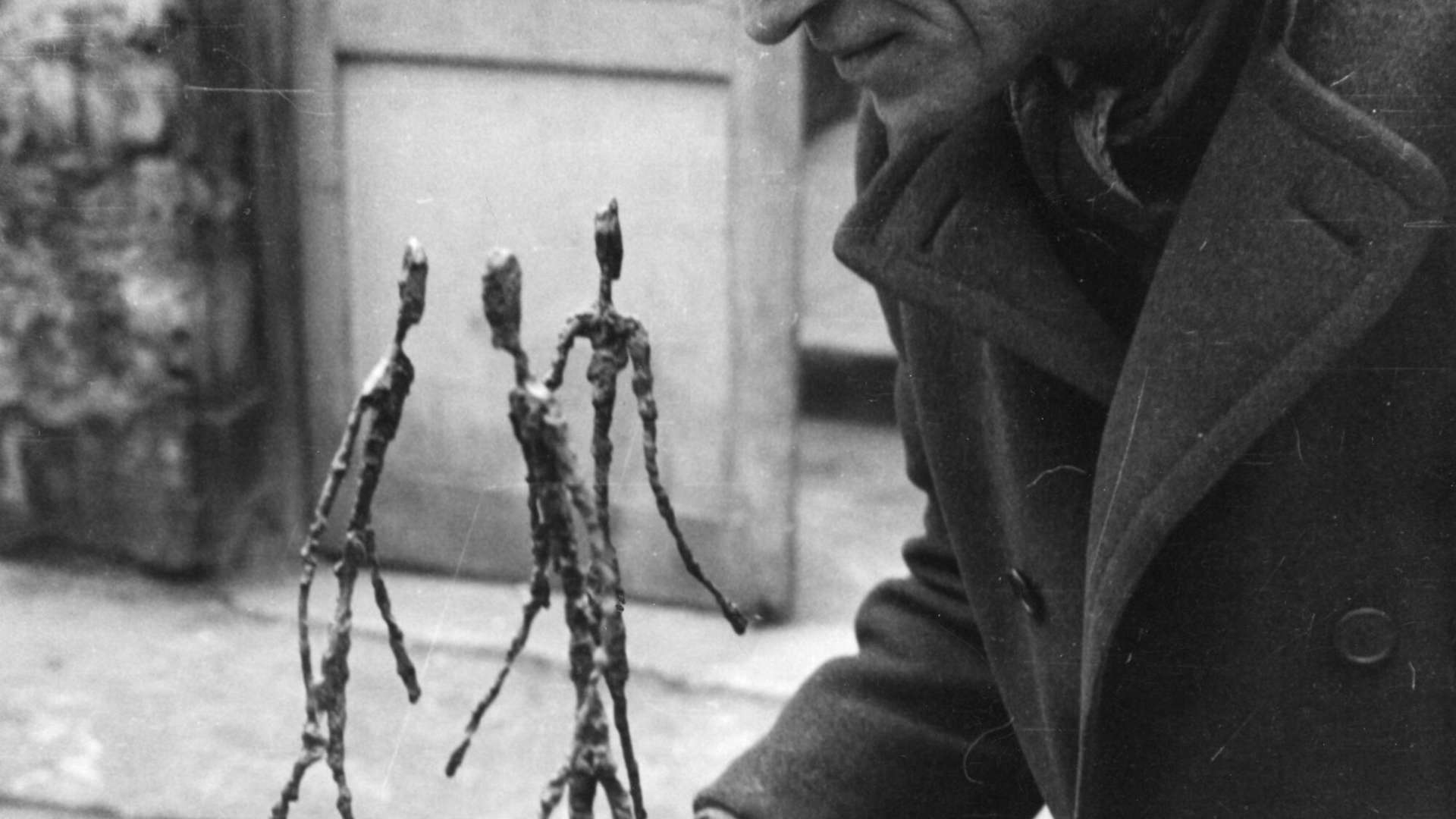 Alberto Giacometti holding the sculpture "Three men walking", 1940, Archives Foundation Giacometti | Courtesy &copy; Succession Alberto Giacometti ADAGP, Paris