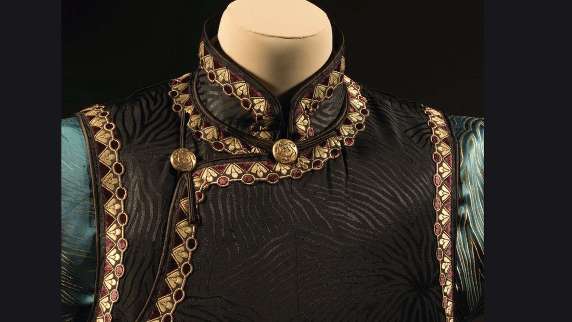 Qipao: Glamour and Modernity beyond Shanghai, Blusa in seta jacquard color acquamarina con maniche a campana e motivo beige a venature / Gilet lungo in seta damascata nera con motivo a venature | Courtesy The Shanghai Museum